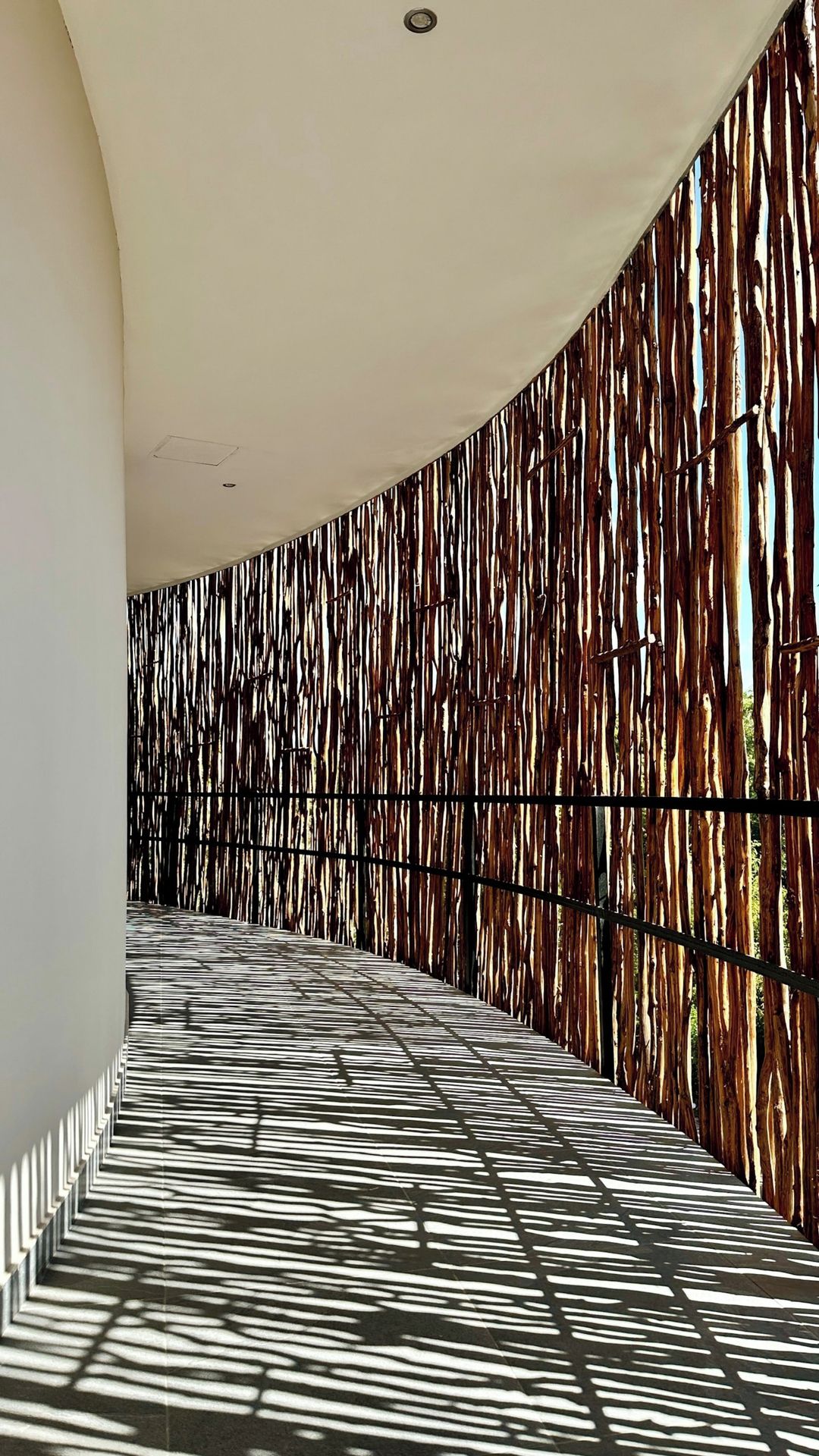 Un couloir doté d’un sol à motifs et d’un mur recouvert de lattes de bois verticales.