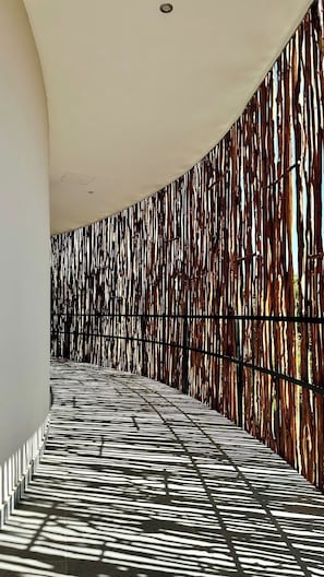 Ein Korridor mit einem gemusterten Boden und einer Wand mit vertikalen Holzlamellen.