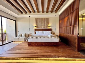 A modern bedroom with a large bed, wooden ceiling beams, a hanging light fixture, and a sliding glass door to a balcony. - Relaxing Lakeside Retreat Pool Hot Tub and Patio (Tulum)