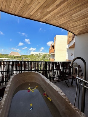 An outdoor hot tub with a wooden ceiling and a view of buildings and trees. - Relaxing Lakeside Retreat Pool Hot Tub and Patio (Tulum)