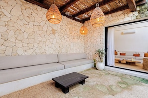 A stone wall interior with a sofa, a wooden bench, and two hanging light fixtures. - Please note: electricity is not included in reservations longer than 28... (Tulum)
