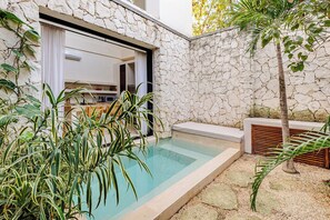 A modern outdoor pool area with a stone wall, a small seating area, and lush greenery. - Please note: electricity is not included in reservations longer than 28... (Tulum)