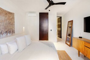 A modern hotel room with a bed, a wooden wardrobe, a large mirror, and a wall-mounted air conditioning unit. - Please note: electricity is not included in reservations longer than 28... (Tulum)