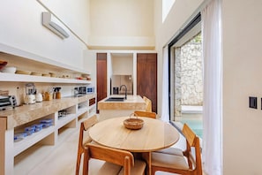 A modern kitchen with a dining area, a built-in oven, and a stone wall. - Please note: electricity is not included in reservations longer than 28... (Tulum)