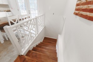 Un escalier avec une rampe blanche menant à un palier.