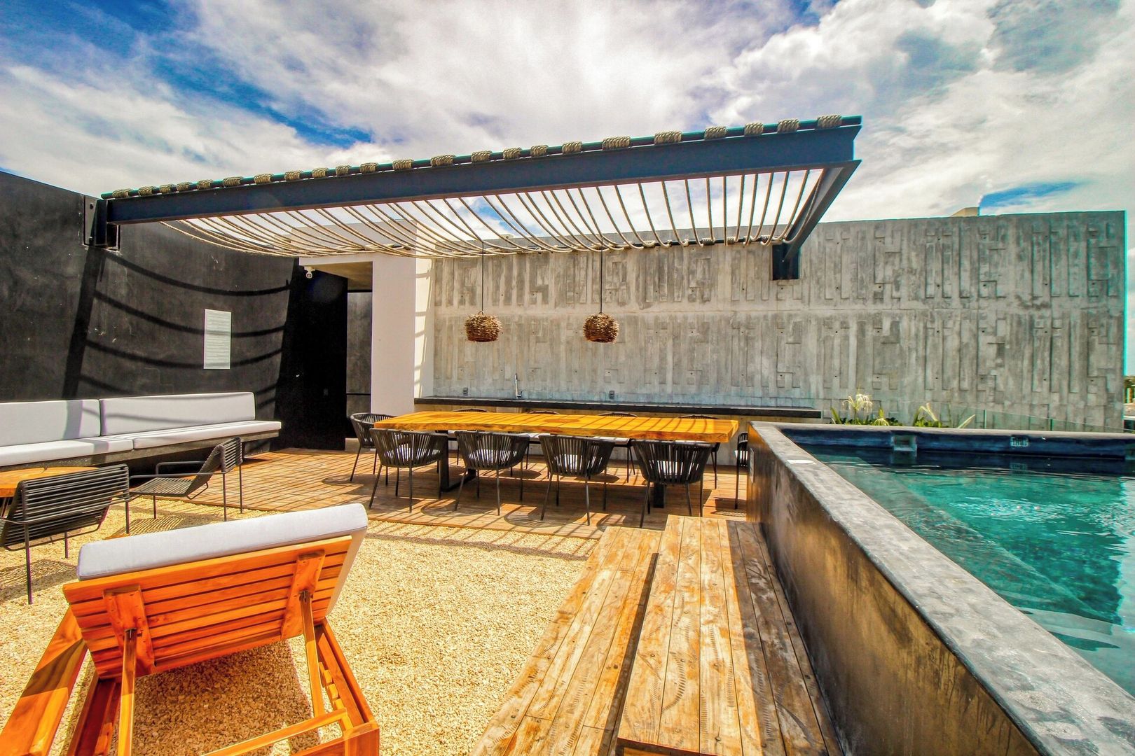 An outdoor pool area with a wooden deck, seating, and a covered patio.