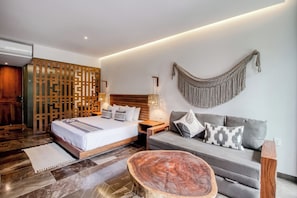 A modern bedroom with a bed, a grey sofa, a wooden coffee table, a decorative wall hanging, and a wooden partition. - Embrace the ultimate Tulum experience in our exclusive loft, perfectly... (Tulum)