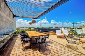A rooftop terrace with a wooden table and chairs, lounge chairs, and a view of the cityscape. - Embrace the ultimate Tulum experience in our exclusive loft, perfectly... (Tulum)