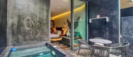 A spa area with a hot tub, a seating area with chairs, and a view into a living space with a sofa and a lamp.