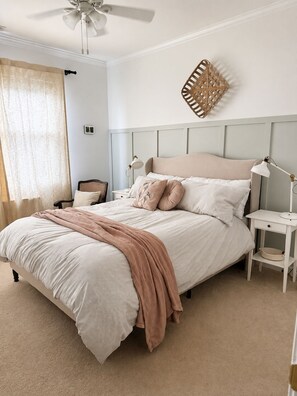 Ein Schlafzimmer mit einem Bett, Nachttischen, einem Deckenventilator und einem an der Wand befestigten Dekorationsobjekt.