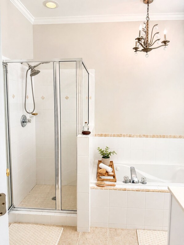 Ein modernes Badezimmer mit einer Glaskabine zur Dusche, einer freistehenden Badewanne und einer Chandelier.