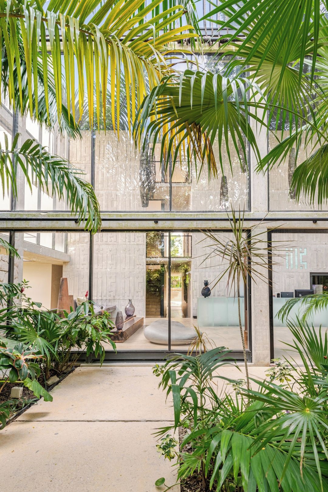 A modern interior with a glass ceiling, indoor plants, and a stone wall.