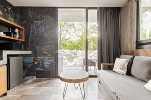 A modern living room with a sofa, a round table, and a mural of a leopard. - Centrally located loft in Tulum · pools and hot tubs (Tulum)