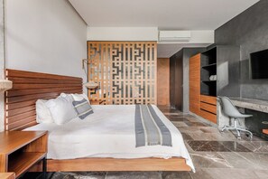 A modern bedroom with a wooden headboard, a bed with white bedding, a desk with a chair, and a TV mounted on the wall. - Centrally located loft in Tulum · pools and hot tubs (Tulum)