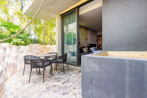 A patio with a stone floor, a table with chairs, and a view of the interior through a glass door. - Centrally located loft in Tulum · pools and hot tubs (Tulum)