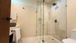 A modern bathroom with a glass-enclosed shower, a white toilet, and a wooden door. - Please note: electricity is not included in reservations longer than 28... (Tulum)