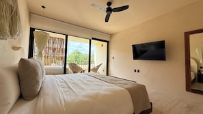 A bedroom with a bed, a television mounted on the wall, and a view of the outdoors through a sliding door. - Please note: electricity is not included in reservations longer than 28... (Tulum)