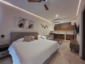 A modern bedroom with a large bed, a sofa, a dining area, and a kitchen. - Private terrace with jungle views (Tulum)