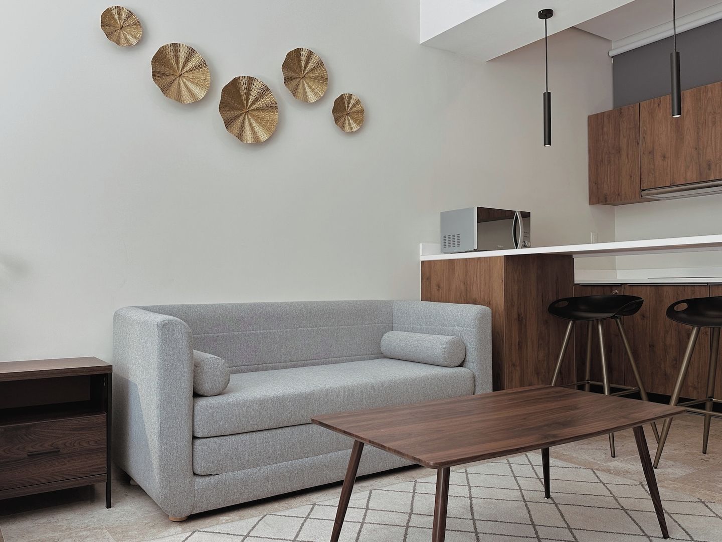 Una sala moderna con un sofá gris, una mesa de centro de madera y decoración en la pared.