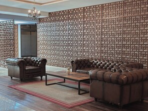 A modern living room with leather sofas, a coffee table, and a patterned wall. - Private terrace with jungle views (Tulum)