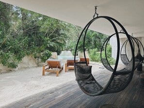 A wooden deck with hanging chairs and a table, surrounded by lush greenery. - Please note: electricity is not included in reservations longer than 28... (Tulum)