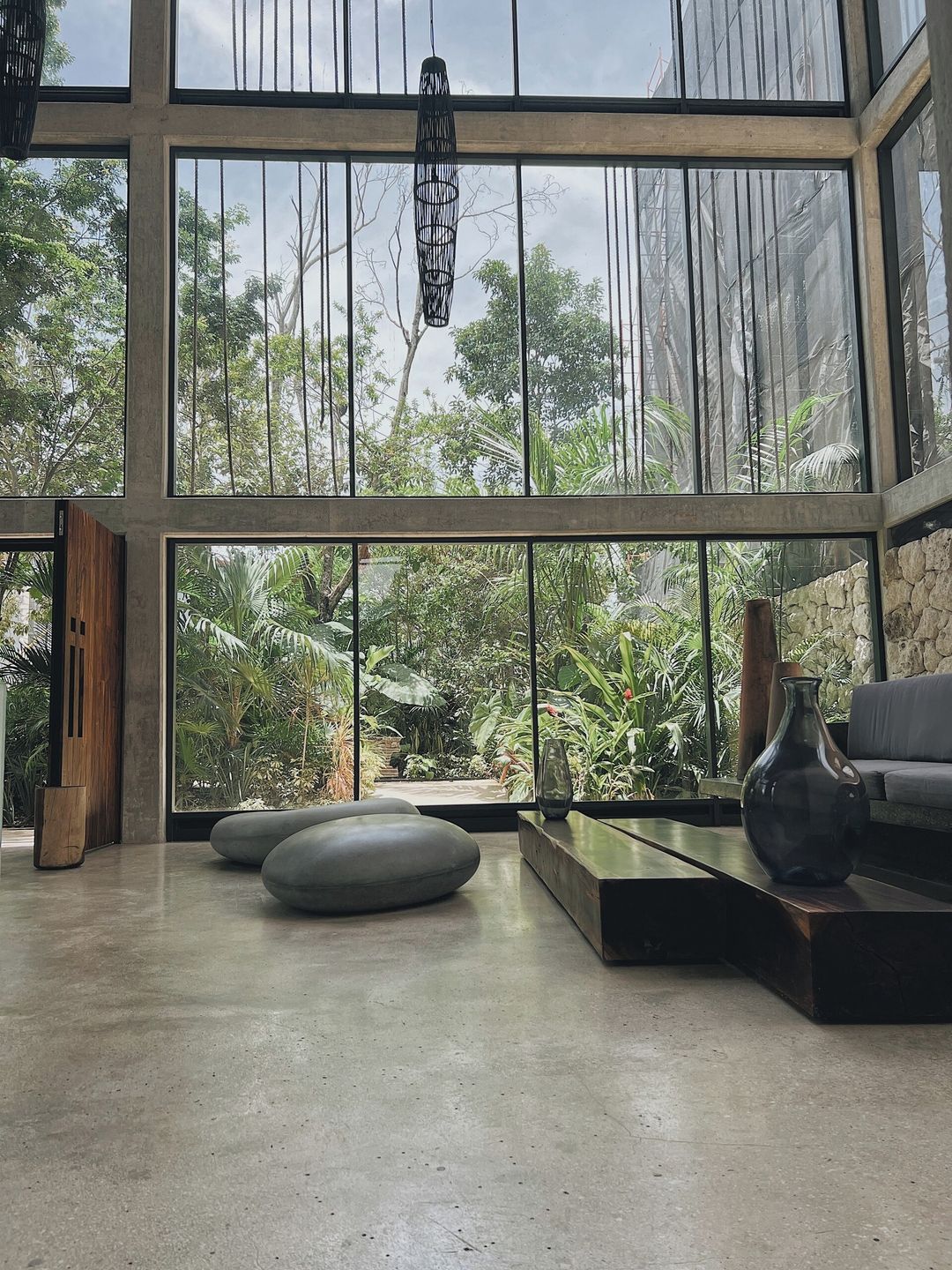 A modern interior with large windows, a stone wall, and a seating area with a sofa and a coffee table.