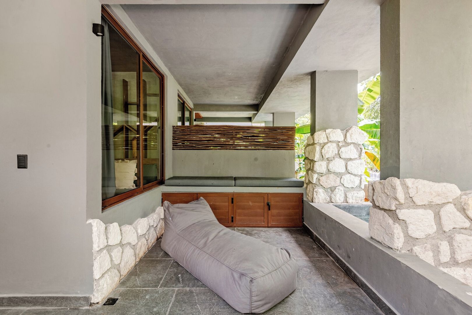 A modern bathroom with a stone wall, a bench, and a window.
