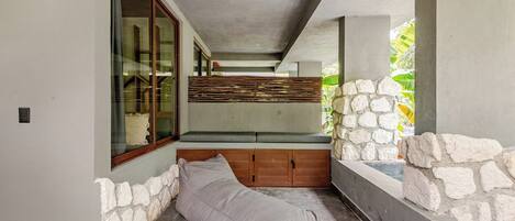 A modern bathroom with a stone wall, a bench, and a window.