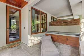 A room with a stone wall, a bench, a wooden cabinet, and a glass door leading outside. - Private pool without stairs · 1BR · Selva Tulum (Tulum)