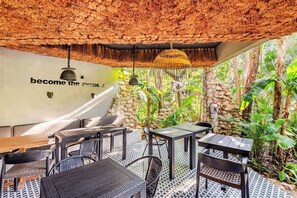 Un espace extérieur aménagé avec des meubles en osier, un mur en pierre et un toit de chaume.