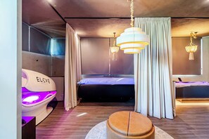 Ein modernes Schlafzimmer mit einem Bett, einem Massagesessel und einem großen Spiegel.