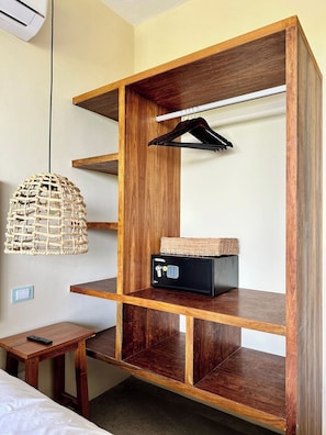 Ein Holzbodenregal mit einer Pendelleuchte, einem kleinen Tisch und einem schwarzen Safe.