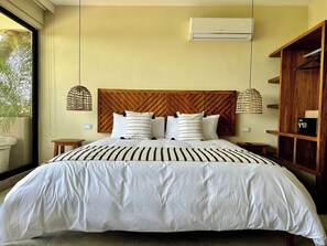 Ein Schlafzimmer mit einem großen Bett, einem Holz-Kopfteil, Nachttischen, einem Holzschrank und einem Fenster mit Blick auf Grünflächen.
