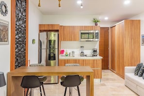 A modern kitchen with wooden cabinets, a stainless steel refrigerator, a microwave, and a coffee maker. - Caminando a la 5a Ave y la playa (Playa del Carmen)