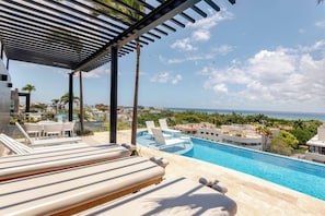A poolside area with lounge chairs and a view of the ocean. - Caminando a la 5a Ave y la playa (Playa del Carmen)