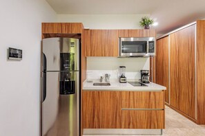 Eine moderne Küche mit einem Edelstahl-Kühlschrank, einer Mikrowelle und einer Kaffeemaschine auf der Arbeitsfläche.