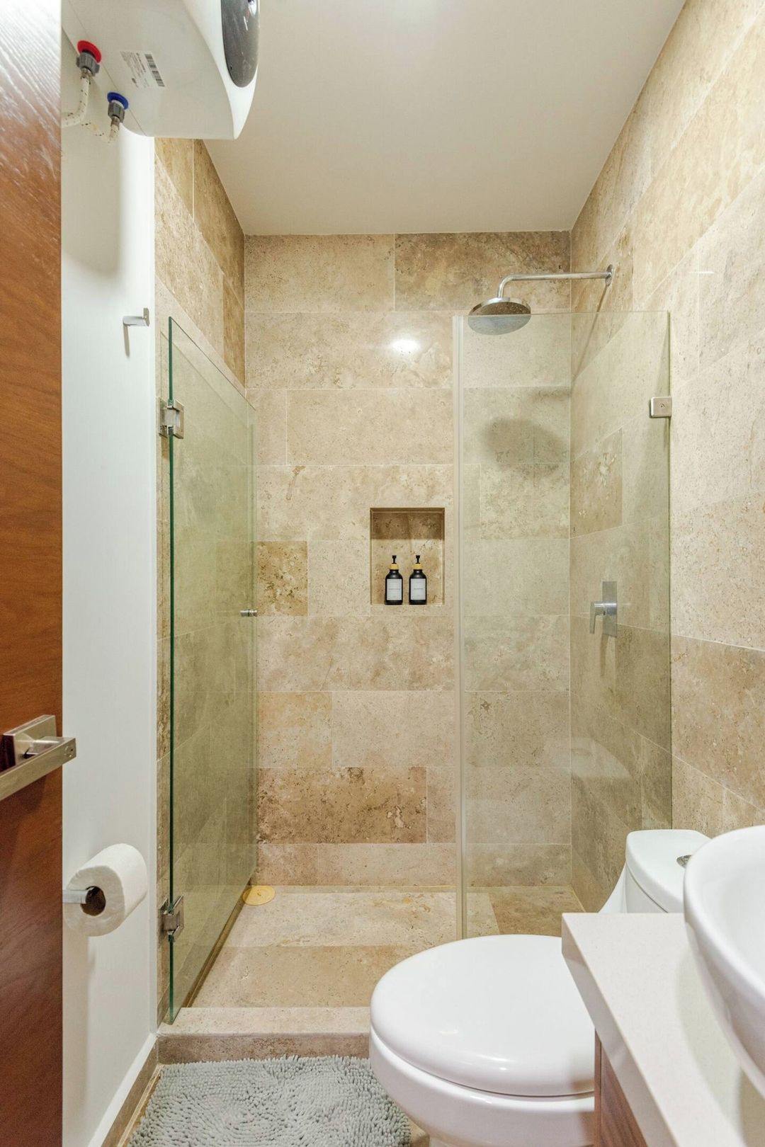 Une salle de bain avec une douche à parois de verre, des toilettes et un lavabo.