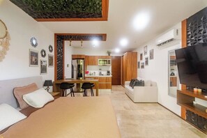 Ein moderner Wohnraum mit einem großen Bett, einem Essbereich, einer Küche und einem Fernseher.