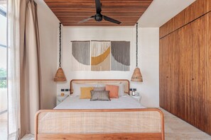 Ein Schlafzimmer mit einem Bett, Nachttischen, einer Pendelleuchte und einem hölzernen Deckenventilator.