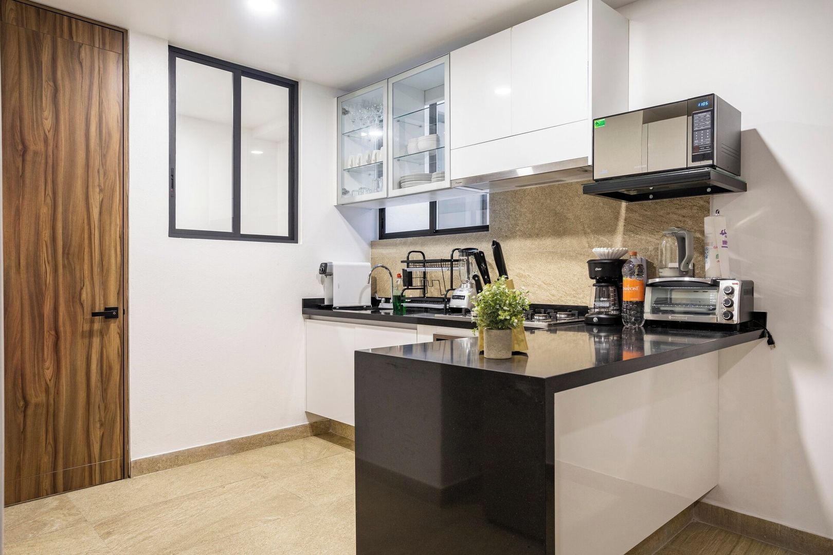 Una cucina moderna con un piano di lavoro nero, mobili bianchi e un forno a microonde integrato.