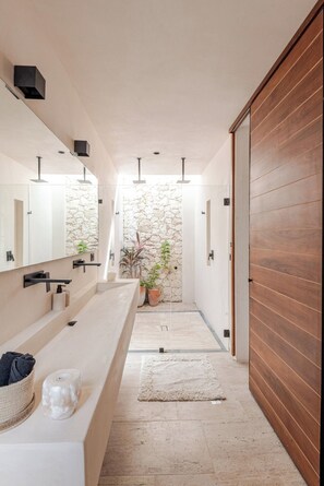 Ein modernes Badezimmer mit einer langen Ablage, einer Steinwand und einer Holztür.