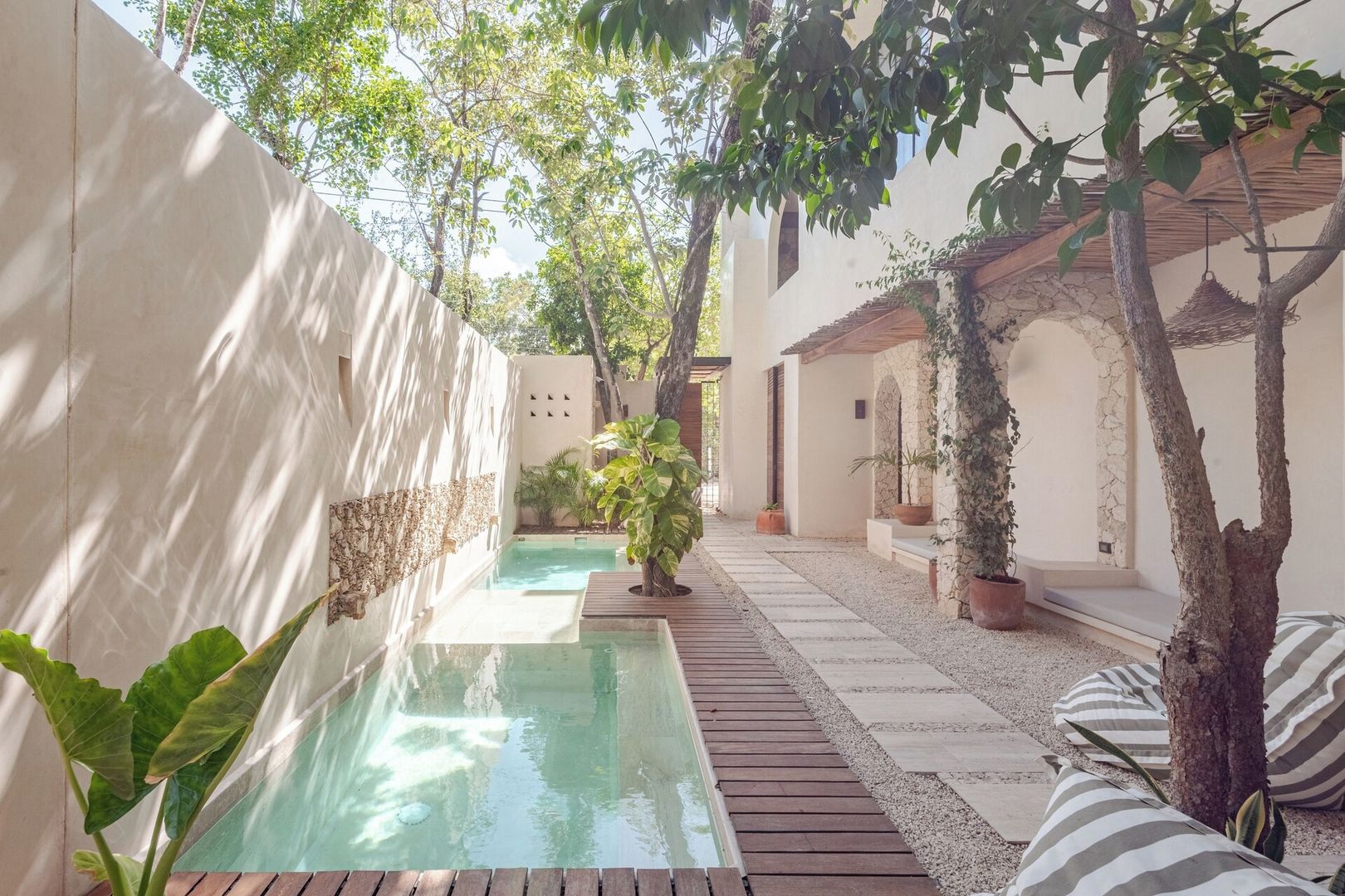 A serene courtyard with a pool, potted plants, and a wooden deck.