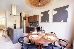 Eine moderne Küche mit einer zentralen Kochinsel, dunklen Holzschränken und einem Edelstahlkühlschrank.