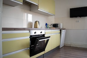 Una cocina con microondas, hervidor y detergente de platos en la encimera.