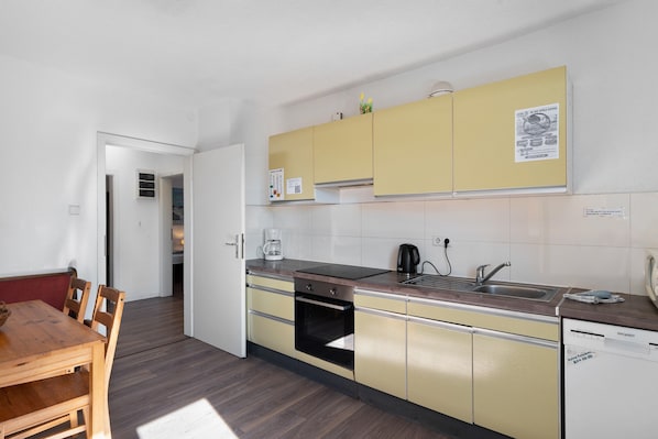 Una cocina compacta con armarios amarillos, horno integrado, cafetera y lavavajillas.