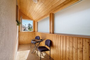 Une pièce aux murs lambrés, avec une table et deux chaises, une fenêtre et une vue sur l’extérieur.