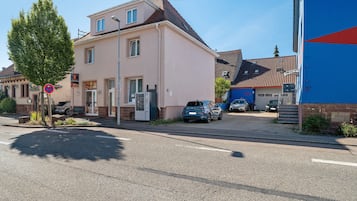 Ein zweigeschossiges Gebäude mit flachem Dach, einer sichtbaren Garagentür und einem geparkten Auto davor.