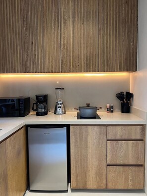 A modern kitchen with wooden cabinets, a built-in microwave, a coffee maker, a blender, a pot, and a dishwasher. - Romantic design with pool island (Tulum)