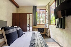 Ein Schlafzimmer mit einem Bett, einem Schreibtisch und einem Fenster mit Vorhängen.