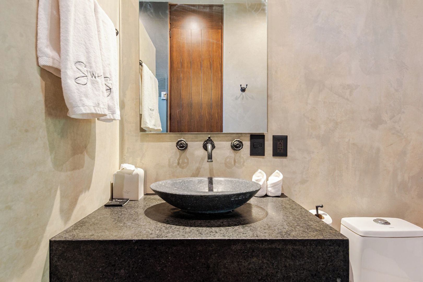 A bathroom with a large mirror, a vessel sink, and a towel rack.